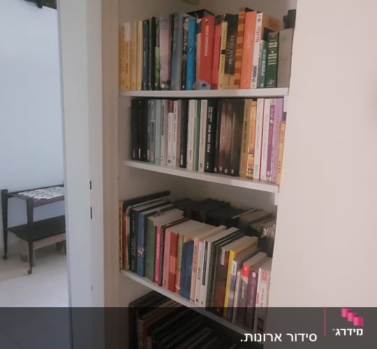 מדף ספרים מלא בספרים מסודרים בצפיפות